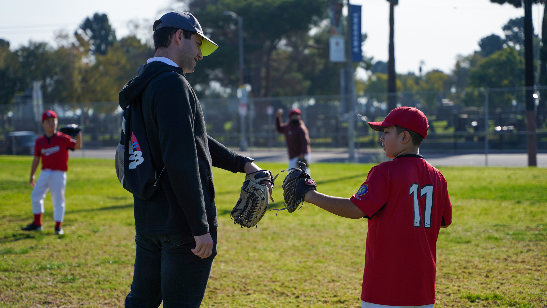 Picture of Ben Wanger and PlayLA participant doing a fist bump with baseball gloves