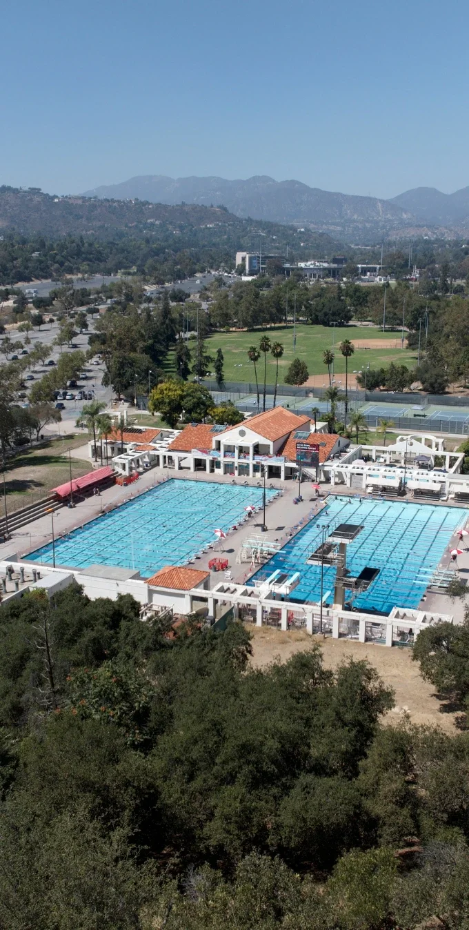 Aerial photograph of the Rose Bowl Aquatics Center showing a pool in the middle with trees and the hillside of the Arroyo Seco Canyon around the Aquatics Center.