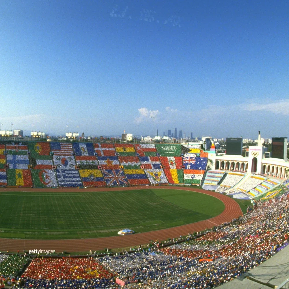 The Los Angeles Memorial Coliseum during the 1984 Games with fans in the stands holding up signs that make up different international flags 