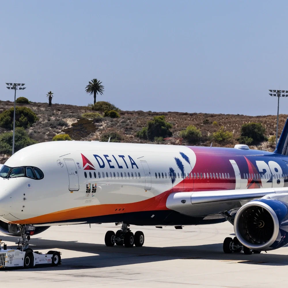 Delta LA28 page shown with the nose facing the camera at an angle and the bluffs in El Segundo in the background of the photograph.