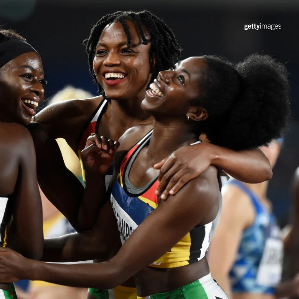 Gemma Acheampong looking above and hugging her teammates while wearing a Team Ghana track uniform