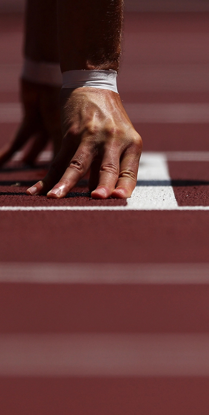 Photograph of hands with taped fingers at the start of a track starting line