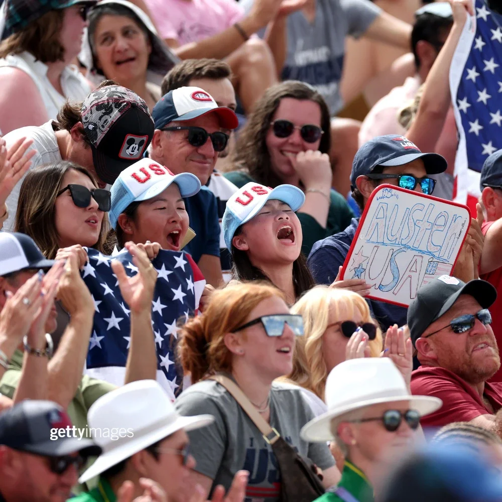 Group of fans cheering at the Olympic Games, many of them wearing Team USA gear. 