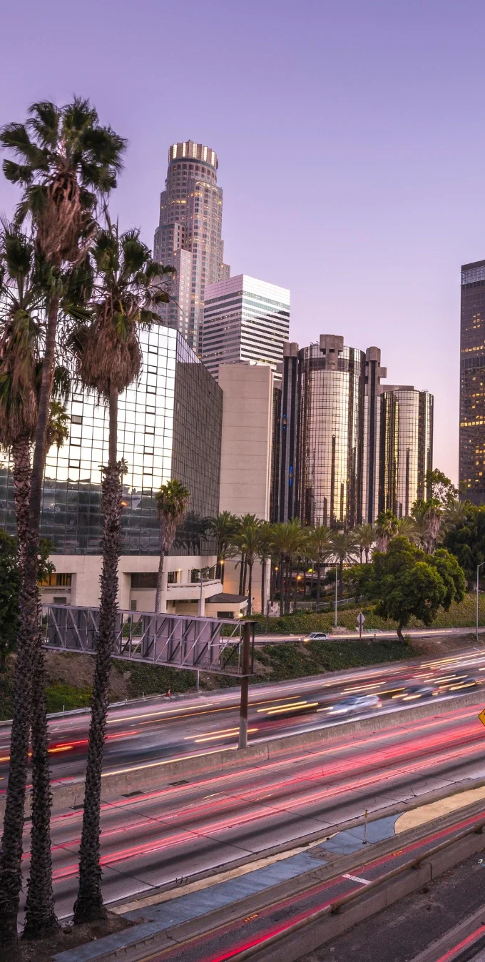 Los Angeles downtown skyline as seen from the 110 Freeway, the freeway is in blur motion at the forefront with skyskapers and palm trees in the background