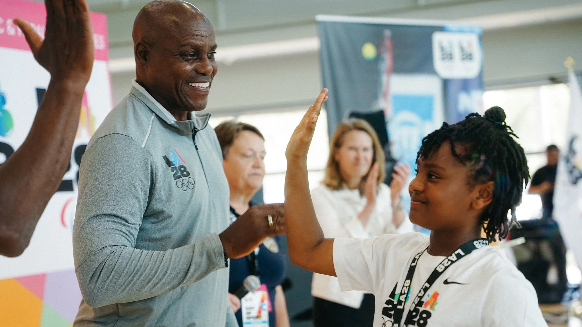 Olympian Carl Lewis giving a high five to a youth participant at Day of Sport