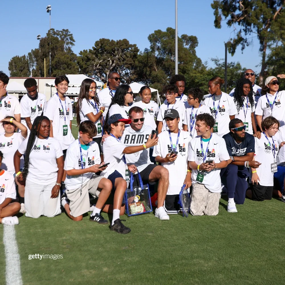 LA Rams Head Coach Sean McVay surrounded by children in white LA28 t-shirts
