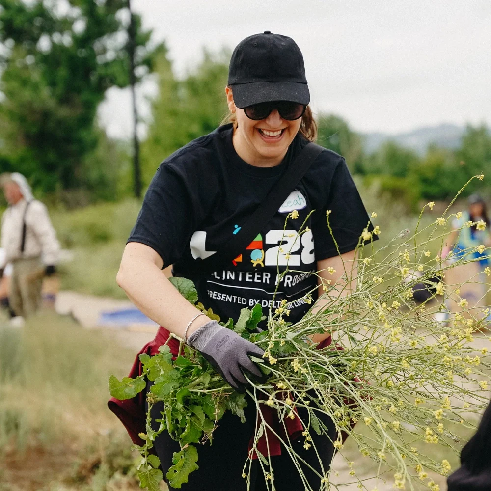 LA28 community volunteer smiling and cleaning up yard