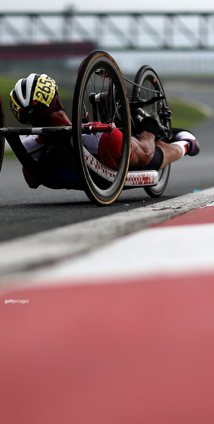 A paralympian cyclist is cycling on a handcycle on an open road