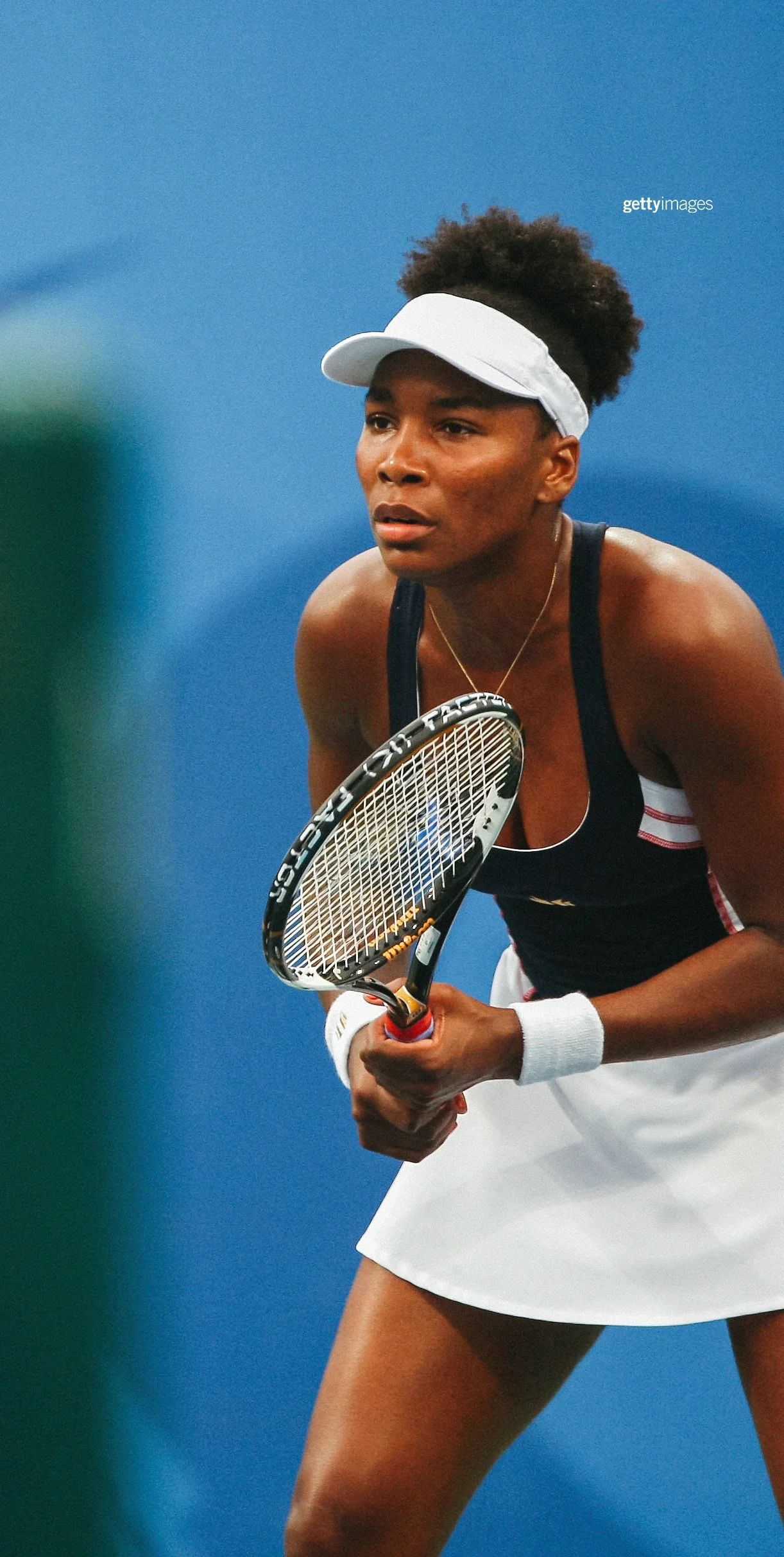 Venus Williams holding a tennis racket on the tennis court while bending to get ready for play during the 2008 Beijing Olympics