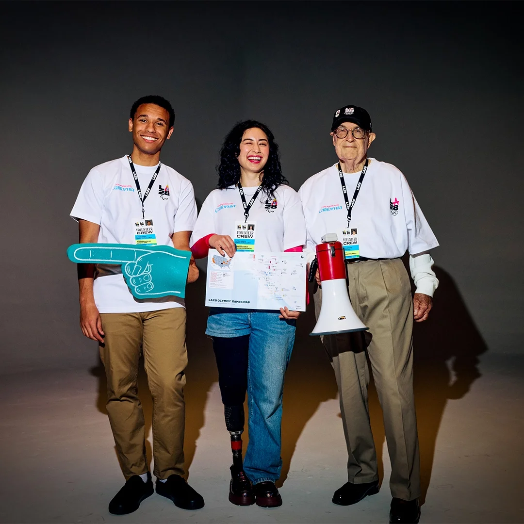Picture of LA28 games-time volunteer crew holding a foam finger, a map and a megaphone