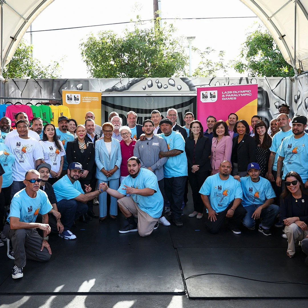 Members of LA28 staff and members of Homeboy Industries pose outside for a photo at the Homeboy Industries headquarters in Los Angeles. 