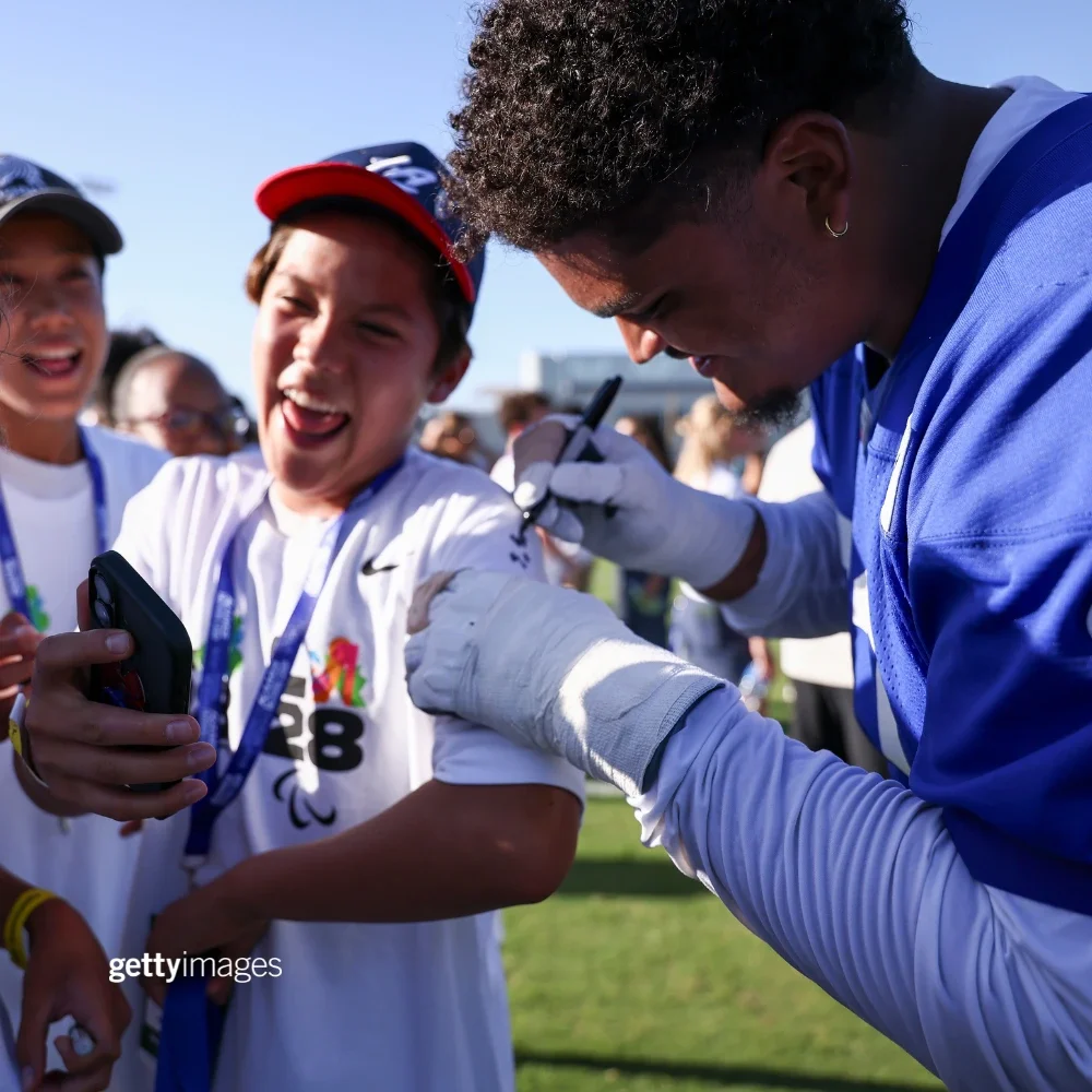 LA Rams player signing an autograph for a kid wearing a baseball cap