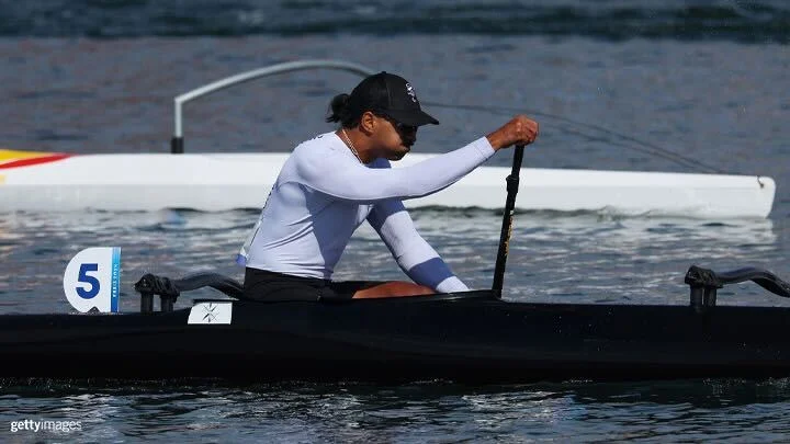 Photograph of Peter Cowan of New Zealand in a long white sleeved shirt and black baseball cap competing in the Men's Va'a Single 200m L3 on day nine of the Paris 2024 Summer Paralympic Games. 