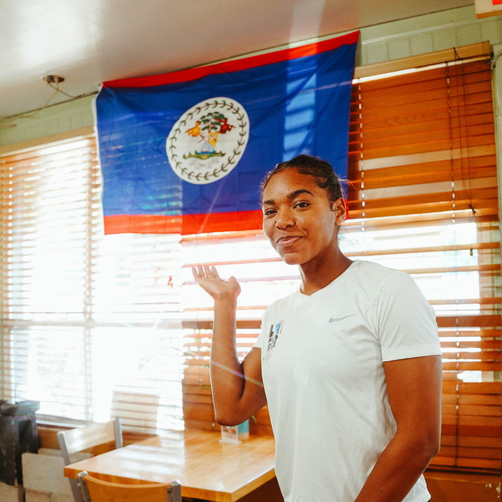 Sam Dirks standing in front of the national flag of Belize