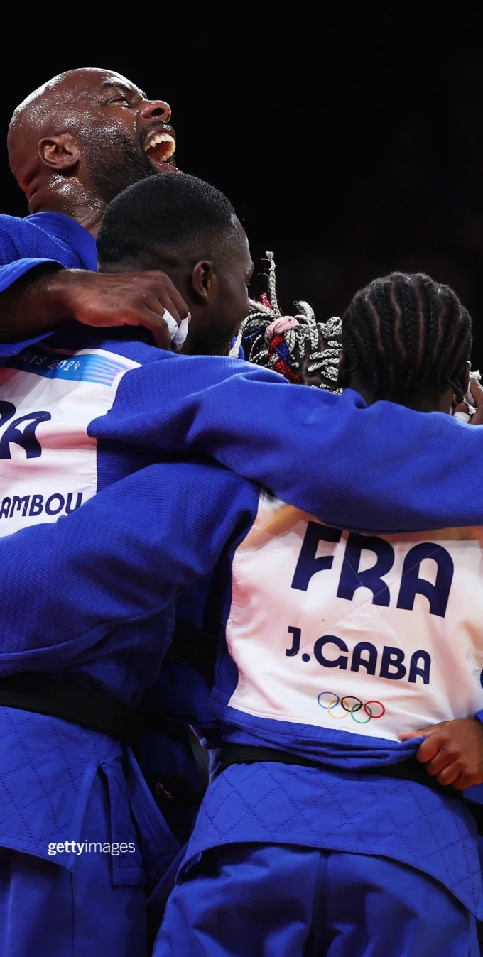 Group of judo Olympic athletes hugging each other in blue uniforms