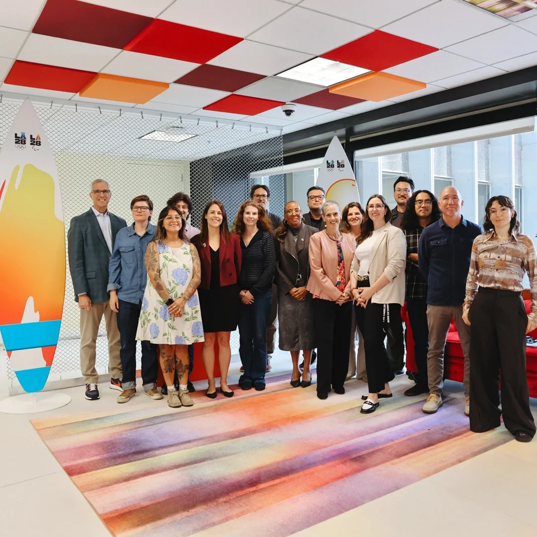 LA28 CEO Reynold Hoover standing with the recipient grantees of the LA28 Resilience Champions Fund initiative inside an indoor conference room