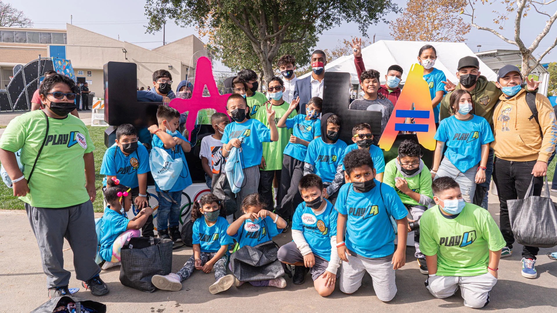 Group photo of participants of the PlayLa Program wearing green and blue shirts that say PlayLA and face masks