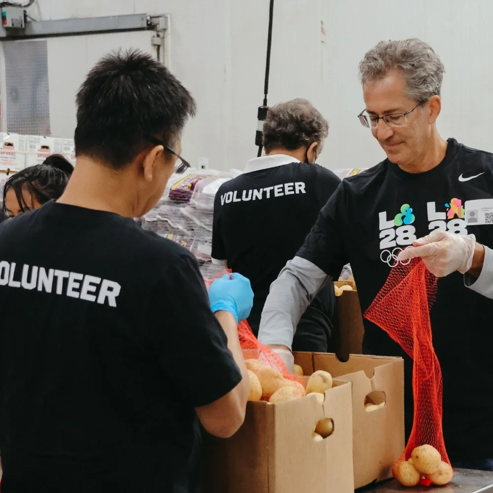 A group of volunteers sorting food including a man with grey hair and glasses smiling down