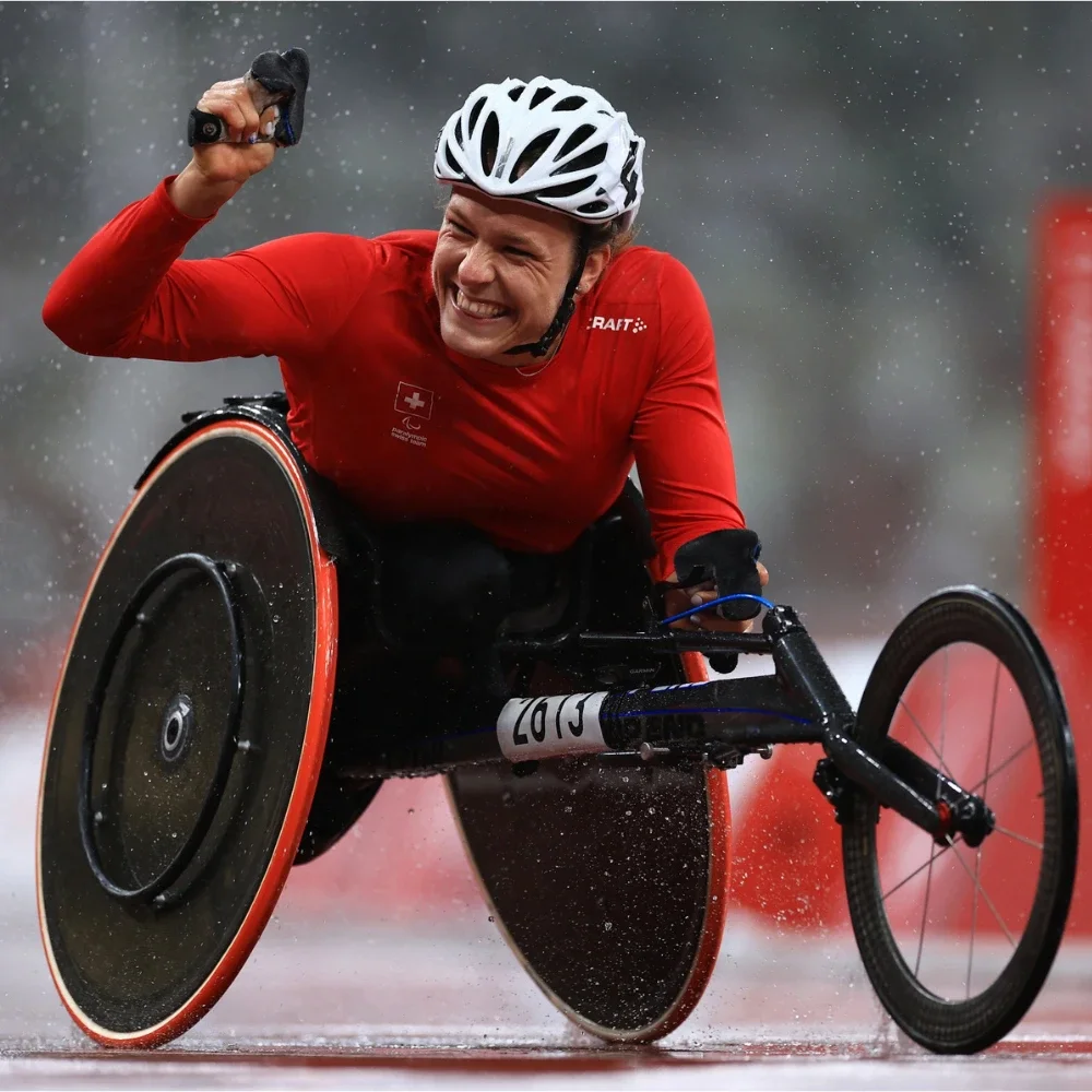 A photo of a Paralympian road cyclist athlete with their fist raised while wearing a long sleeved red shirt