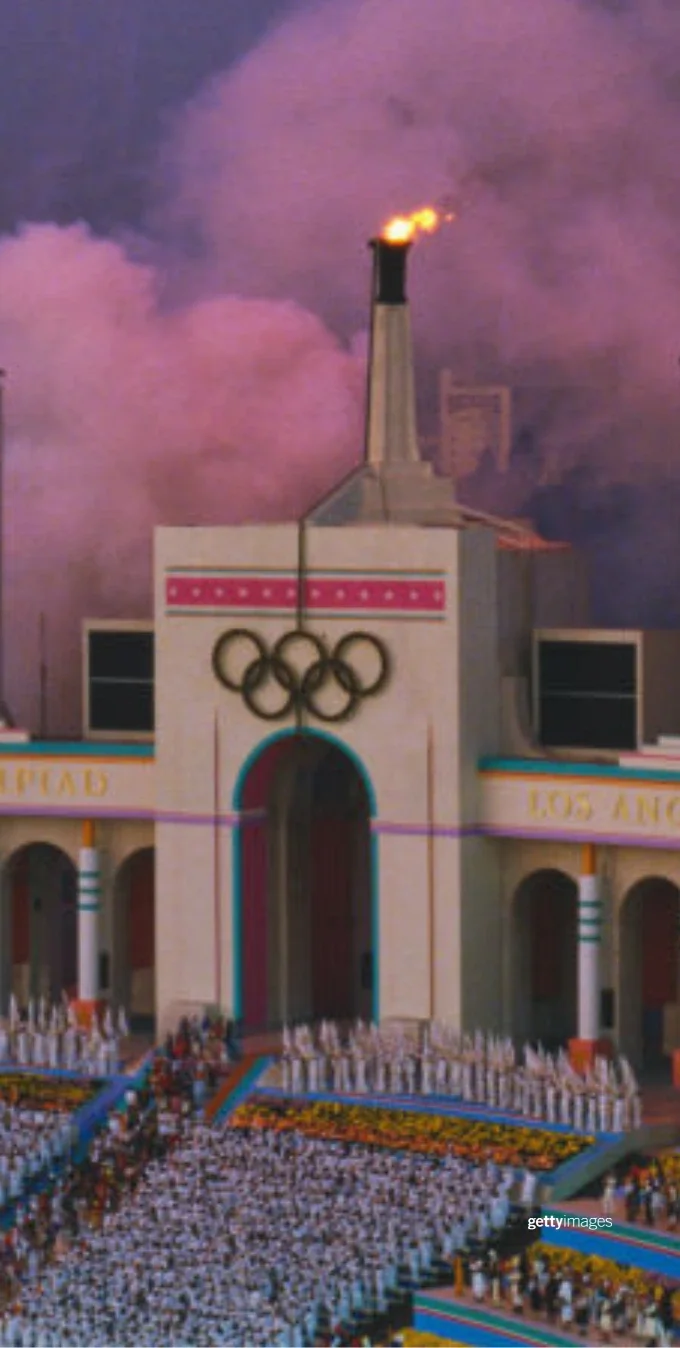 A photograph of the coliseum during the Closing Ceremonies of the LA 1984 Games. The photo shows the Coliseum and two screens, with the left screen having the words "Good Luck to the athletes of the world".