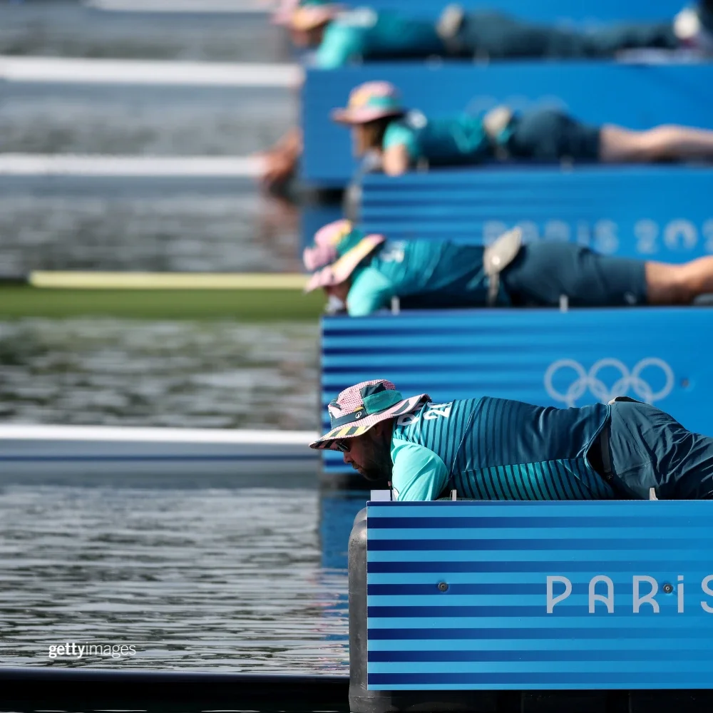 Paris Games-Time volunteers helping hold canoes steady in the water while they are laying down belly first