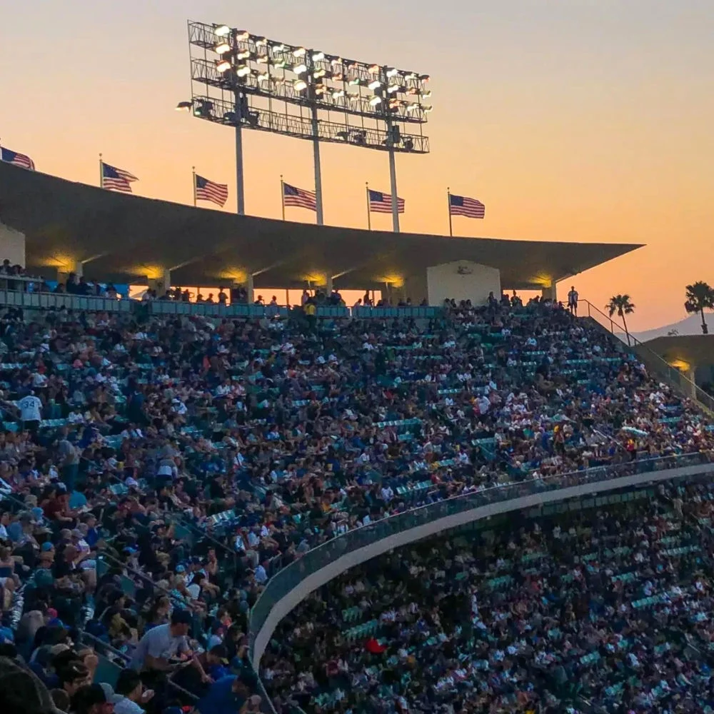 photo of a stadium full of 1000s of people in the crowd at sunset