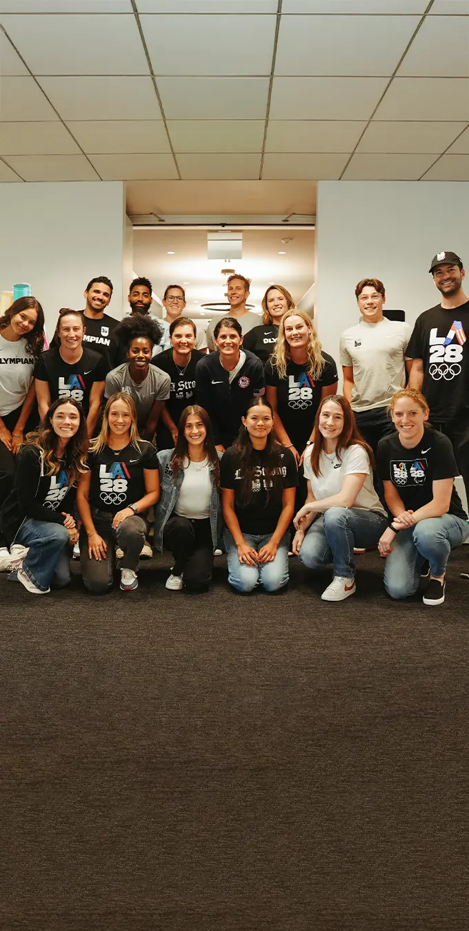 A photograph of the LA28 Athlete Fellows in front of a LA28 emblem at the LA28 headquarters