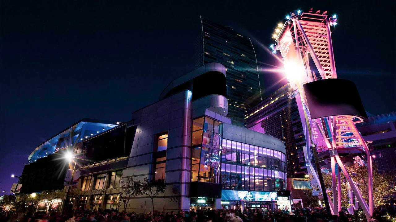 Photograph of the Peacock Theater at night showing the front of the building lit up with purple, pink and orange lights and lots of people standing outside on the street around the building,