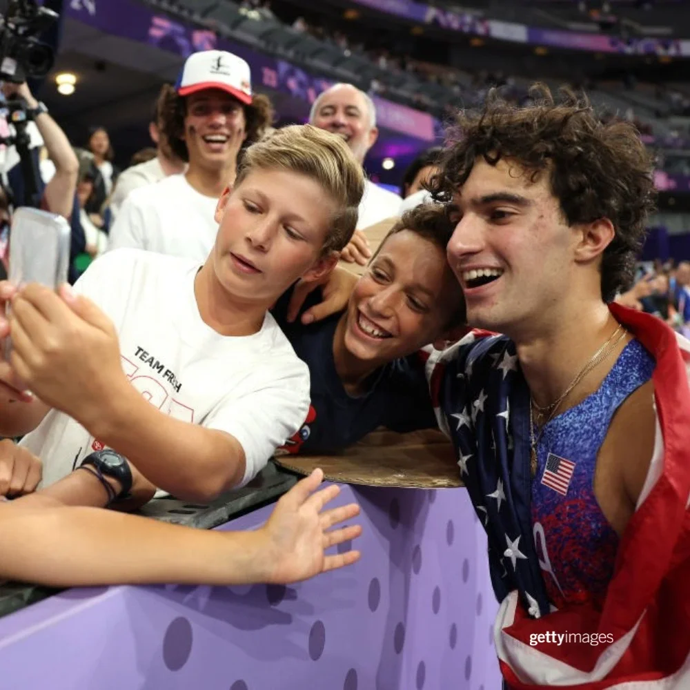 Three young boys take a selfie with Team USA Paralympian Ezra Frech at the Paris 2024 Summer Games.