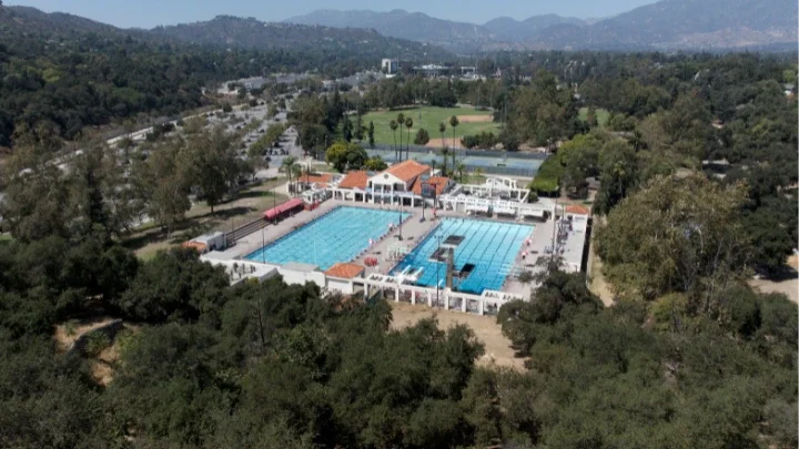 Aerial photograph of the Rose Bowl Aquatics Center showing a pool in the middle with trees and the hillside of the Arroyo Seco Canyon around the Aquatics Center.