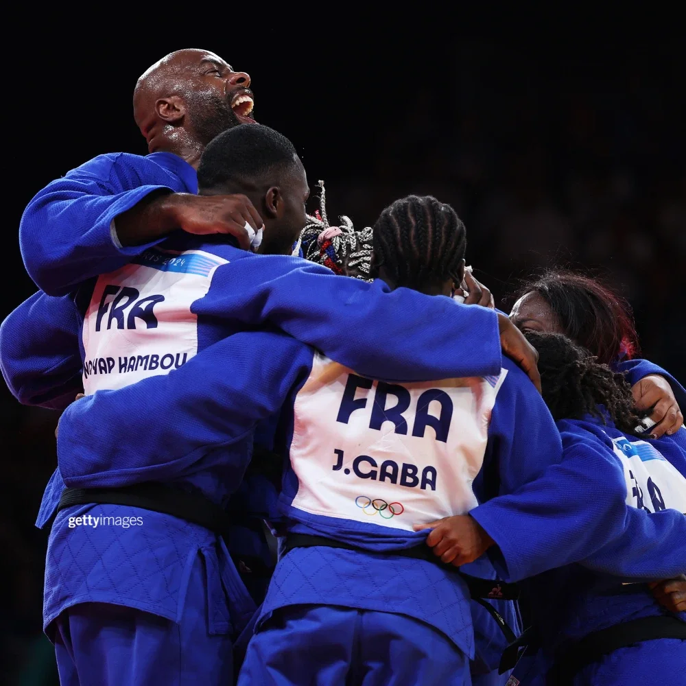 A photo of a group of French judo athletes hugging in a circle