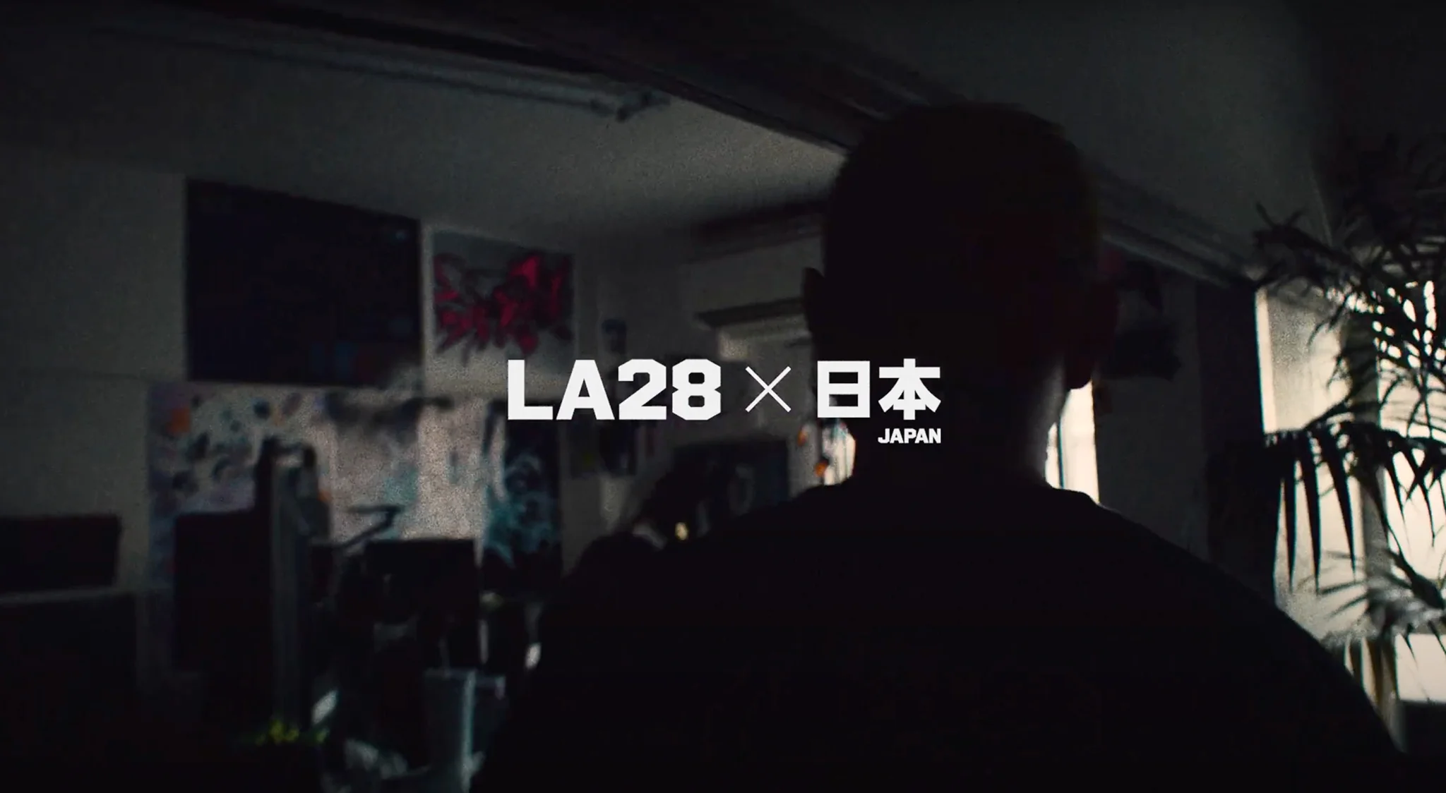 Dark photo of someone from behind with an LA28 logo and Japanese kanji saying Japan