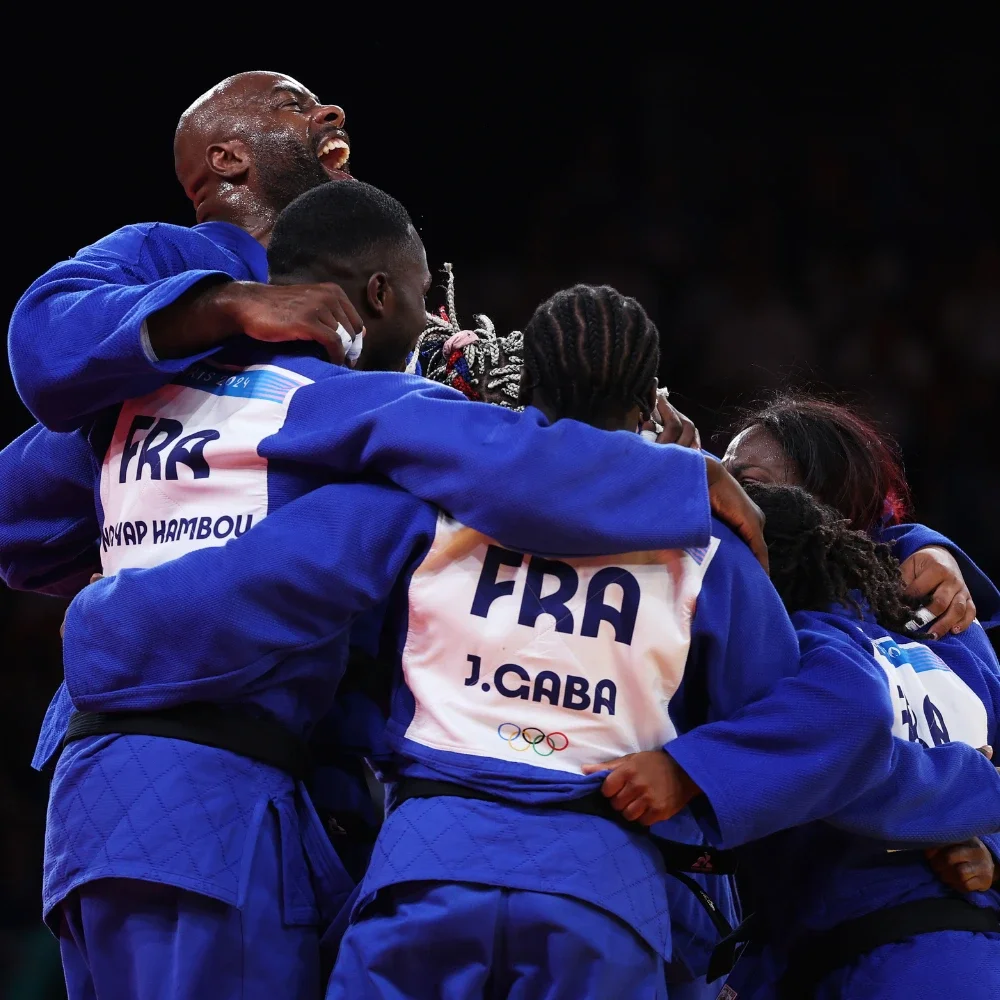 A photo of a group of French judo athletes hugging in a circle