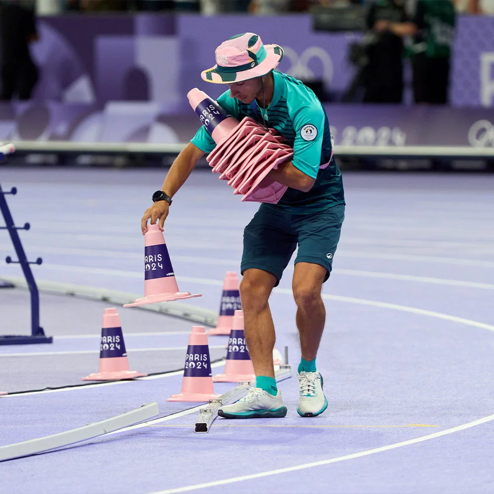 A photo of a Volunteer setting up cones for a Track & Field event