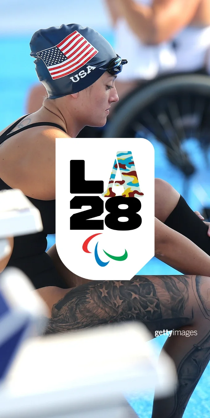 A photograph of paralympic swimmer Elizabeth Marks seated by a pool in a swimsuit with a Team USA swimming cap and placing her prosthetic leg. The LA28 Camo A is overlay3ed on top of the photograph. 